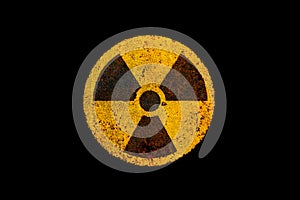 Round yellow and black radioactive ionizing radiation nuclear danger symbol on rusty metal grungy texture and isolated on black