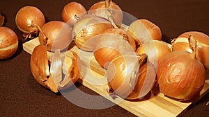 Round yellow onions on wooden board on table