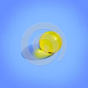 Round yellow pill on blue background. Close up pharmacy health care concept. Organic liquid nutrition, oil photo
