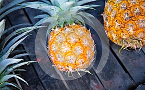 Round yellow pineapple on rustic wooden stall. Ripe pineapple bunch for sale on tropical farm market