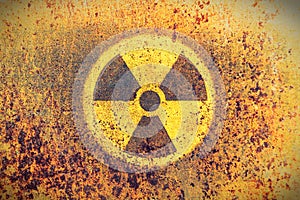 Round yellow radioactive ionizing radiation danger symbol painted on a massive rusty metal wall with rustic grunge texture