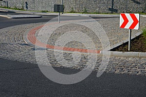 Roundabout of gray granite cubes closer to the center. beveled concrete curbs with flowers and grass in the middle of the circle.