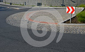 Roundabout of gray granite cubes closer to the center. beveled concrete curbs with flowers and grass in the middle of the circle.