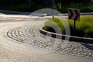 Roundabout of gray granite cubes closer to the center. beveled concrete curbs with flowers and grass in the middle of the circle.