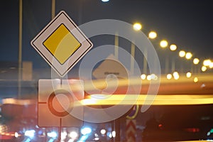 Roundabout road signs with blurred cars on city street traffic at night. Urban transportation concept