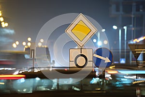 Roundabout road signs with blurred cars on city street traffic at night. Urban transportation concept