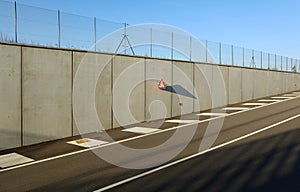 Roundabout warning triangle road sign, on concrete wall at the exit of the underpass.