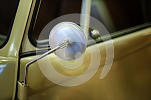 Rounded mirror of a classic yellow colored car