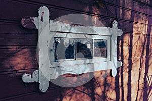 Routed window on an old wall with shadows from trees photo