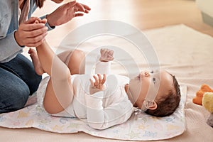 Routine is the route to a secure and happy baby. a woman changing her adorable baby girls diaper at home.
