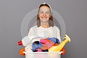 Routine washing keeps garments fresh. Housekeeper maintains clean and tidy house. Smiling cheerful woman wearing whote t-shirt