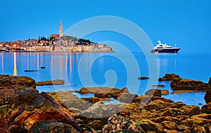 Rovinj, Croatia. Antique medieval old town nighttime view. Luxury yacht and fishing sea. Big stones