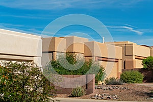 Row of adobe cement houses in late afternoon sun with rock gardens and trees in front yard in late afternoon sun