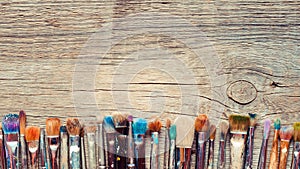 Row of artist paintbrushes closeup on old wooden rustic background