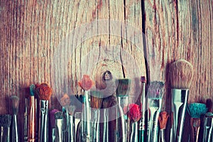 Row of artist paintbrushes closeup on old wooden table, retro st