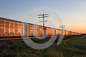 Row of Auto Carrying Train Cars at Sunset on Prairie