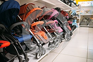 Row of baby strollers on shelf in store, nobody