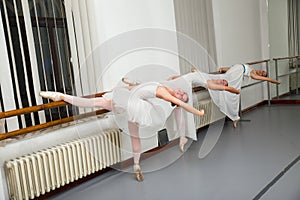 Row of ballet dancers practicing at barre in rehearsal room