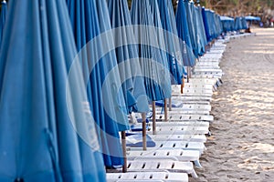 row of beach beds with blue umbrellas