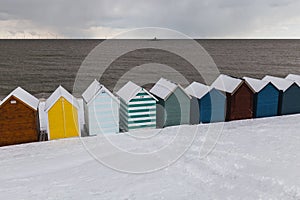 Row of beach huts in winter snow on coast of Herne Bay, Kent, En