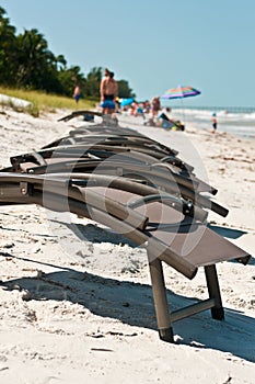 Row of beach, lounge chairs on sandy, tropical beach