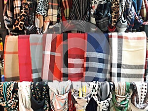 Row of a beautiful colored woman's scarves tied knot to the rack hanging in store,variety of ethnic clothes.