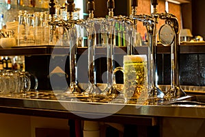 Row of beer taps in a pub with a tankard of beer