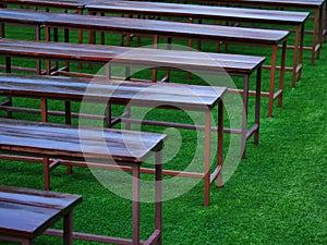 Row of bench on green grass to take a seat for rest in garden or queue