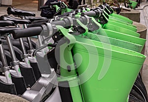 A row of bicycle handlebars, lime green basket and bicycle seat. Public rental bicycle for transportation bike to work and travel