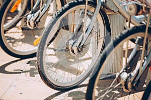 Row Of Bicycles Bikes For Rent On Sidewalk. Close Up Of Wheel