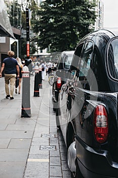 Row of Black cabs parked on a side of the road in City of London, London, UK.