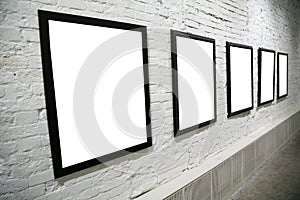 Row of black frames on white brick wall