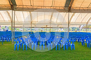 Row of blue chairs plastic on lawn in tent