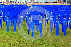 Row of blue chairs plastic on lawn in tent