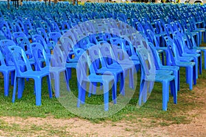 Row of blue chairs plastic on lawn in tent