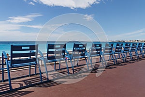 Row of blue chairs on quay in Nice