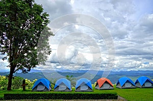 Row of blue and orange camping tents on green grass