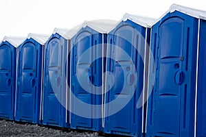 Row of blue portable chemical booths of bio toilets