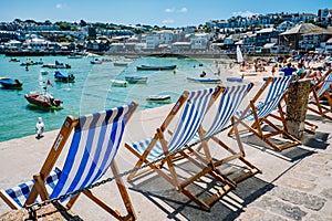 Row of blue and white empty deck chairs overlooking the harbor in bright sunlight