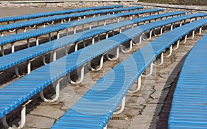 Row of blue wooden seats on a spectator grandstand photo. Bench in the park