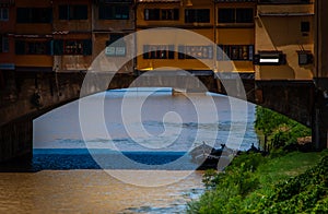 Row boats underneath Pontevecchio bridge in Florence Italy