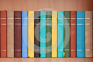 Row of books in wooden cabinet.