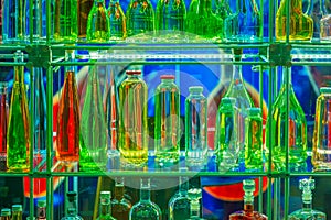 Row bottles for different drinks lit by light, bright background