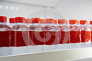 Row of bottles with red beverage on a shelf