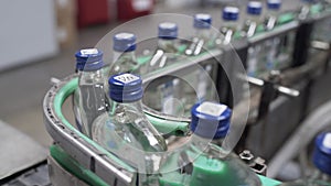 Row of bottles with vodka in conveyor belt in factory production line. Factory for bottling alcoholic beverages. Glass