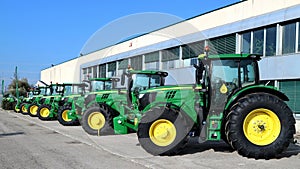 Row of brand new John Deere tractors outside the store of local consortium, exhibition of latest agricultural machinery.