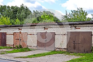 A row of brick garages with rusty metal gates. Russia