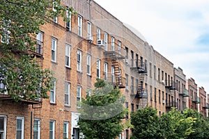 Row of Brick Residential Buildings with Fire Escapes and Green Trees during Spring in Astoria Queens New York