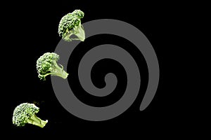 Row of broccoli on a black background. Copy space. Top view