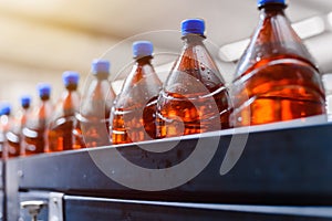 Row of brown beer plastic bottles on beer filling conveyor line